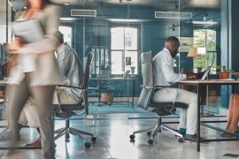 image of busy office with workers walking around or sitting at desks