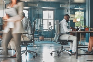 image of busy office with workers walking around or sitting at desks