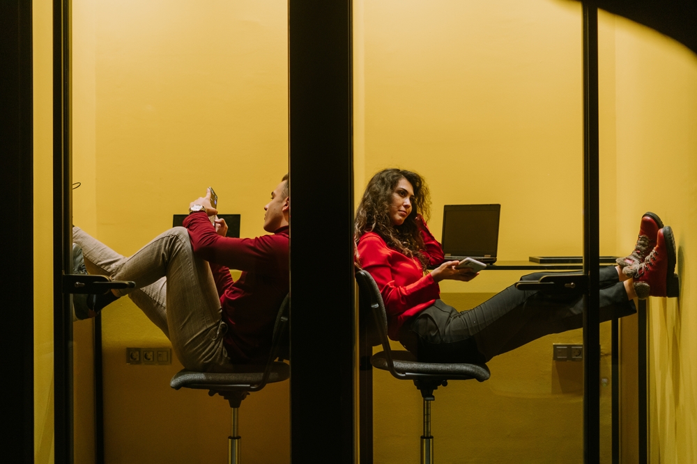 Male and female coworkers having a video call at soundproof phone booth at modern co working space