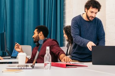 Group of people of different races working concentrated and happy with laptops in a coworking office