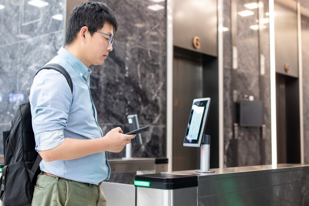 An Asian business man passes through the access control turnstile of the office building by facial recognition