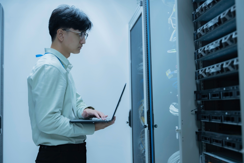 Computer engineer is setting up network in server room,Systems Maintenance Technician,Male engineer working in server room at modern data center