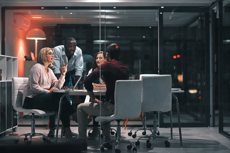 Business meeting, laptop and people for design at night in office, creative agency and overtime food for project. Teamwork, support and problem solving in pizza planning for deadline and discussion