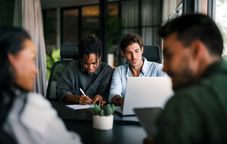 Office Space Per Person: Choosing a Standard That Matches Your Work Style four people working at a table