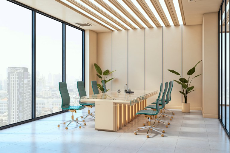 meeting room, with a cream table and walls, large windows, and turquoise office chairs surrounding the table